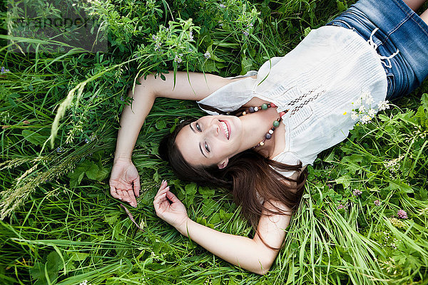 Lächelnde Frau im hohen Gras liegend