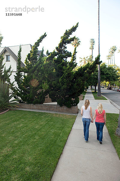 Junges lesbisches Paar beim Gehen auf dem Bürgersteig  Rückansicht