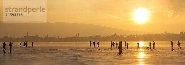 Deutschland  Bodensee Hegne  Silhouetten von Eisläufern und Wanderern vor Reichenau bei Sonnenuntergang