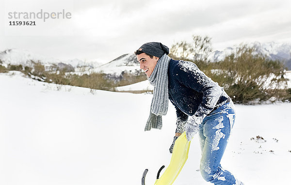 Junger Mann beim Schlittenfahren im Schnee