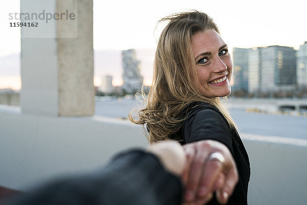 Spanien  Barcelona  Porträt einer glücklichen jungen Frau  die die Hand hält