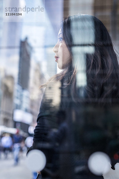 USA  New York City  Manhattan  träumende junge Frau hinter der Glasscheibe