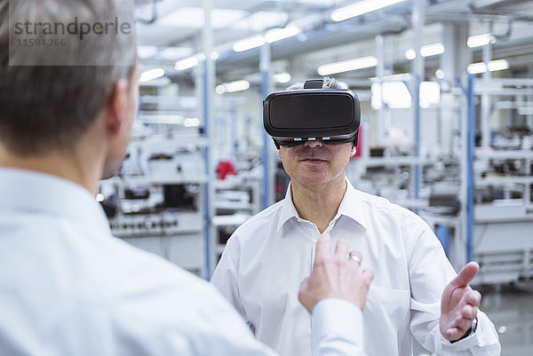 Zwei Manager  die mit einer VR-Brille in der Firma stehen.