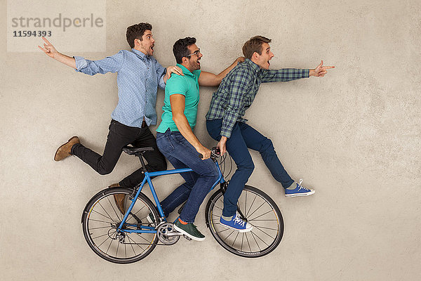 Drei Freunde  die auf einem Fahrrad fahren