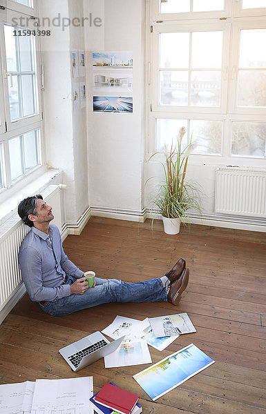 Mann im Büro auf dem Boden sitzend