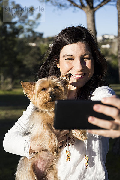 Fröhliche junge Frau nimmt Selfie mit ihrem Hund mit