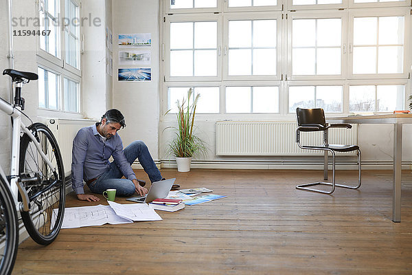 Mann mit Laptop auf dem Boden in einem modernen informellen Büro