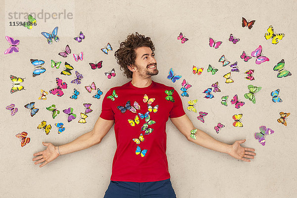 Junger Mann auf dem Rücken liegend mit Schmetterlingen umher