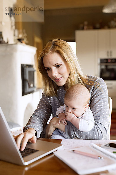 Mutter mit Baby zu Hause mit Laptop