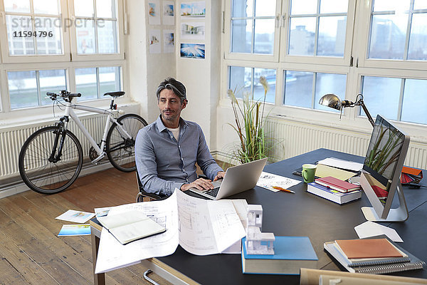 Mann mit Laptop am Schreibtisch im Büro