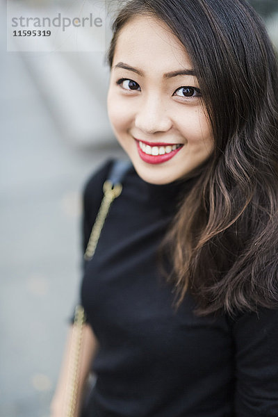 Porträt einer lächelnden jungen Frau in schwarz gekleidet