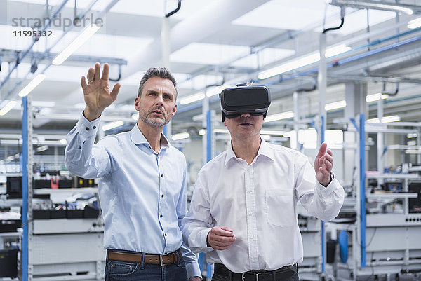 Zwei Manager  die mit einer VR-Brille in der Firma stehen.