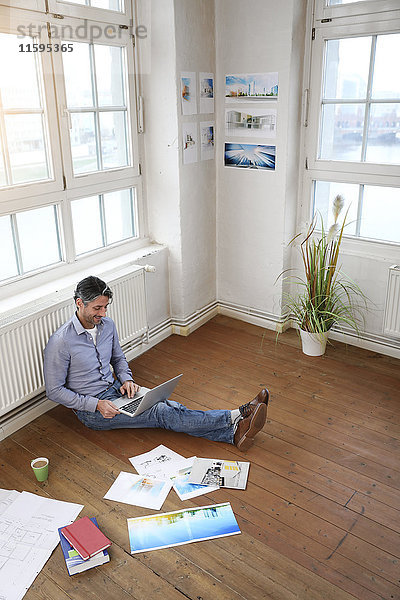 Mann mit Laptop auf dem Boden im Büro