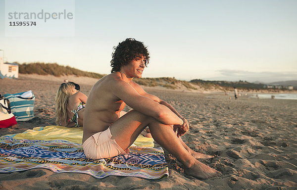 Lächelnder junger Mann entspannt am Strand