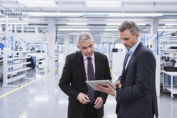 Zwei Manager bei einer Besprechung in einer Fabrikhalle