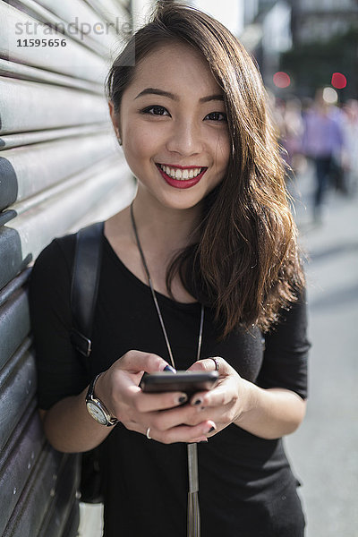 Porträt einer lächelnden jungen Frau mit Handy