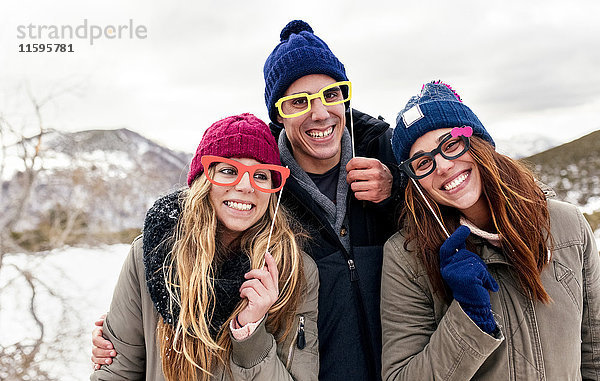 Drei Freunde mit gefälschter Brille haben Spaß in den verschneiten Bergen