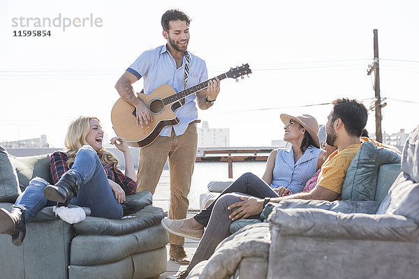 Freunde bei einer Dachparty und Gitarre spielen