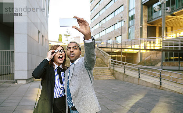 Junger Geschäftsmann und Frau beim Fotografieren von Smartphones