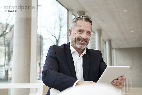 Porträt eines lächelnden Geschäftsmannes mit Tablette