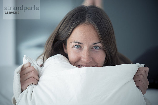 Porträt einer glücklichen jungen Frau auf dem Bett liegend