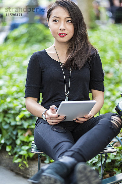 Porträt einer jungen Frau mit Tablette im Stadtpark