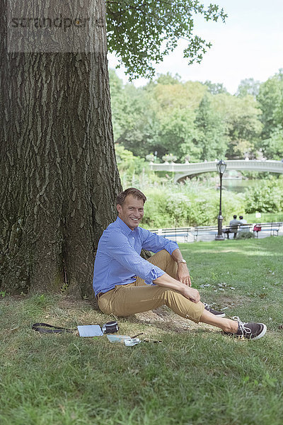 Lächelnder Mann entspannt auf einer Wiese im Park