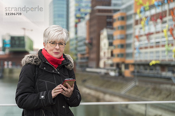 Deutschland  Düsseldorf  Portrait einer älteren Frau mit Handy