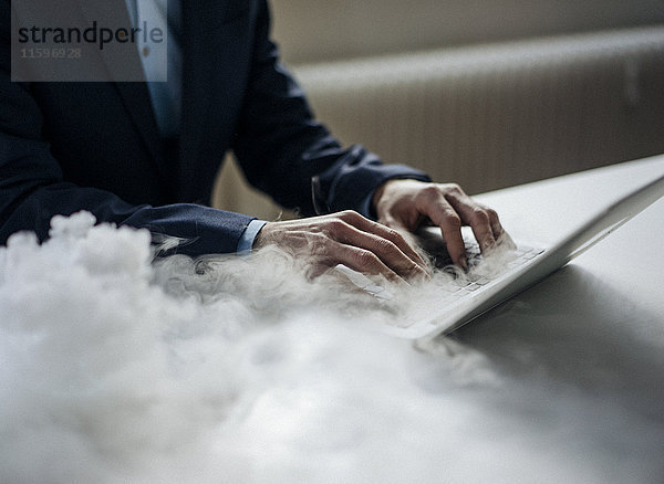 Nahaufnahme eines Geschäftsmannes mit rauchendem Laptop im Büro