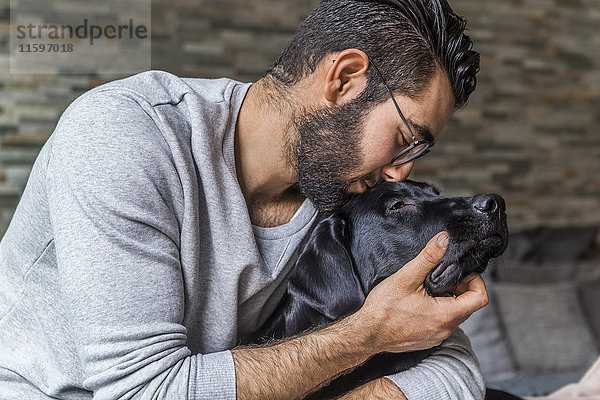 Mann kuschelt mit seinem Hund zu Hause