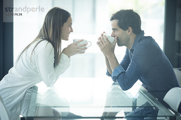 Fröhliches junges Paar am Tisch mit Kaffeetassen