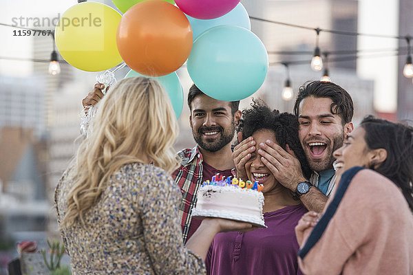 Freunde feiern Geburtstagsparty auf dem Dach mit Geburtstagskuchen