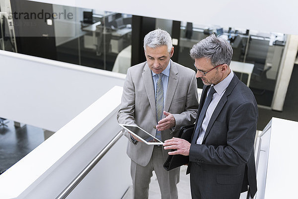 Zwei Geschäftsleute bei einem informellen Treffen mit einem digitalen Tablett