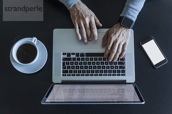 Draufsicht des Geschäftsmannes am Schreibtisch mit Laptop  Smartphone und Tasse Kaffee