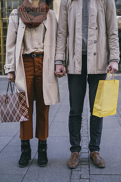 Paar mit Einkaufstaschen  die Händchen halten