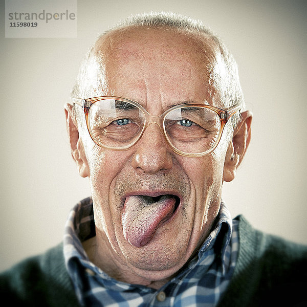 Porträt eines älteren Mannes  der seine Zunge herausstreckt.