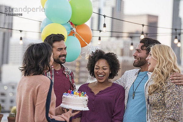 Freunde feiern Geburtstagsparty auf dem Dach mit Geburtstagskuchen