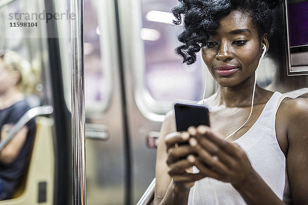 Porträt einer Frau beim Blick auf das Handy in der U-Bahn