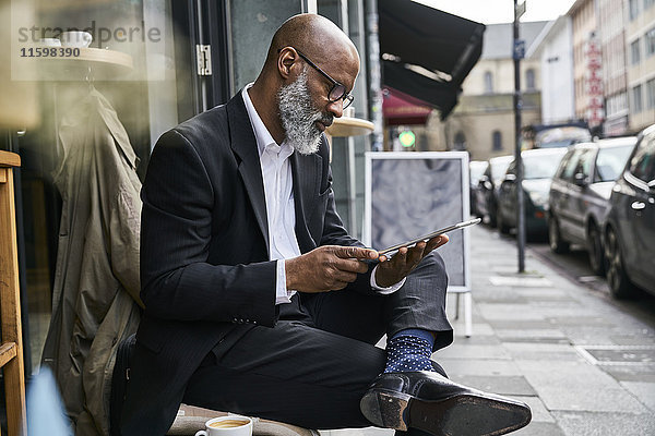 Reife Geschäftsleute sitzen im Cafe mit digitalem Tablett