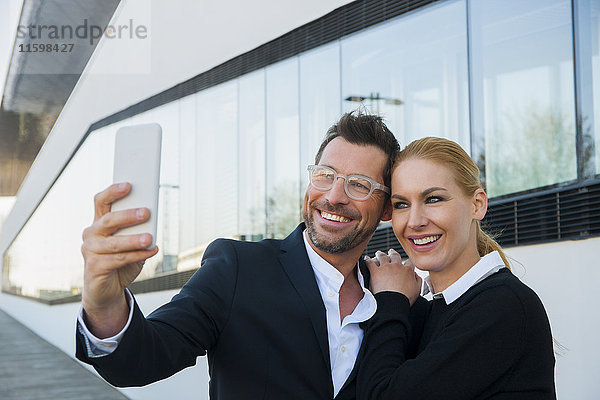 Lächelnder Geschäftsmann mit einer Frau  die einen Selfie nimmt.