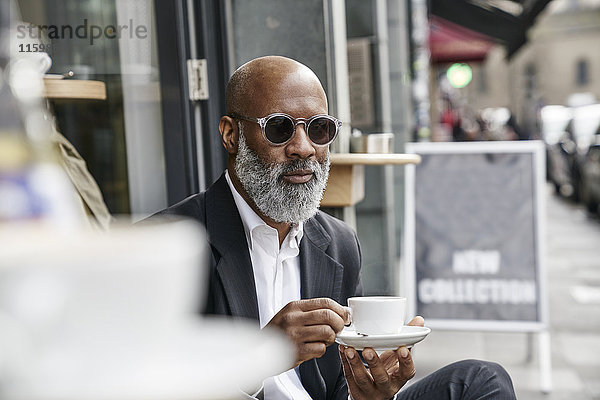 Erwachsener Geschäftsmann trinkt Kaffee im Straßencafé