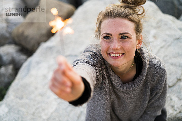 Porträt einer lächelnden jungen Frau mit Wunderkerze im Freien