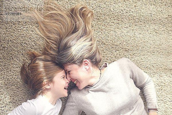 Mutter und Tochter liegen auf dem Teppich und haben Spaß.
