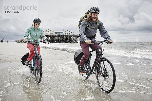 Deutschland  Schleswig-Holstein  St. Peter-Ording  glückliches Paar beim Radfahren am Strand