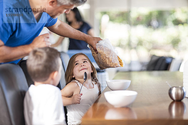Vater bereitet Getreidefrühstück mit Kindern zu