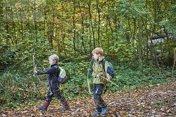 Zwei kleine Jungen mit selbstgemachten Pfeil und Bogen im Herbst