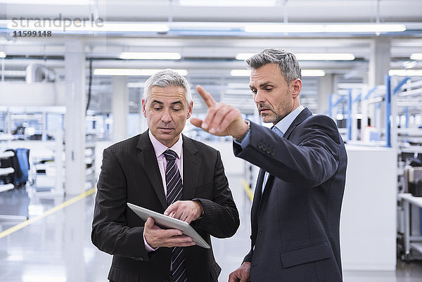 Zwei Manager bei einer Besprechung in einer Fabrikhalle