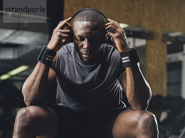 Sportler im Fitnessstudio  Kopfhörer tragend  konzentrierend