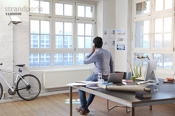 Mann mit Handy in einem modernen informellen Büro