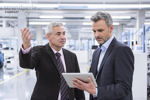 Zwei Manager bei einer Besprechung in einer Fabrikhalle